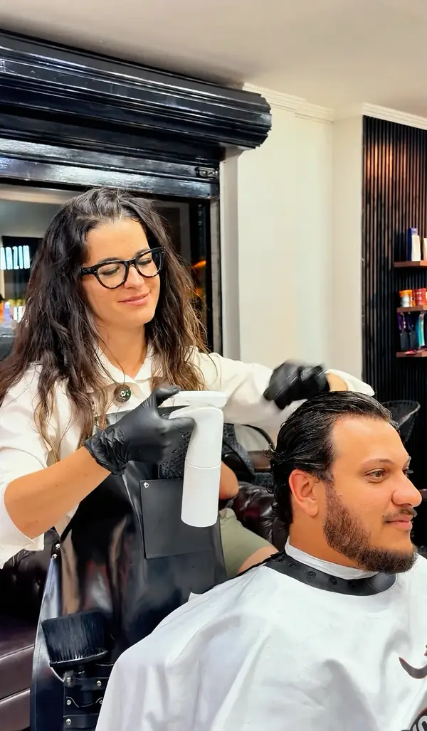 Thathiane Dias preparando o cabelo de um cliente com borrifador
